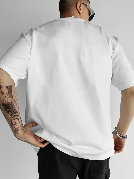 Person wearing a plain white t-shirt with visible tattoos on arms, standing against a neutral background.